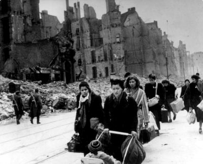 (GERMANY OUT) Stream of refugees and people who have been bombed out of their homes moving through destroyed streets - 1945after end of war; on the left two soviet soldiers patrolling) (Photo by ullstein bild/ullstein bild via Getty Images)